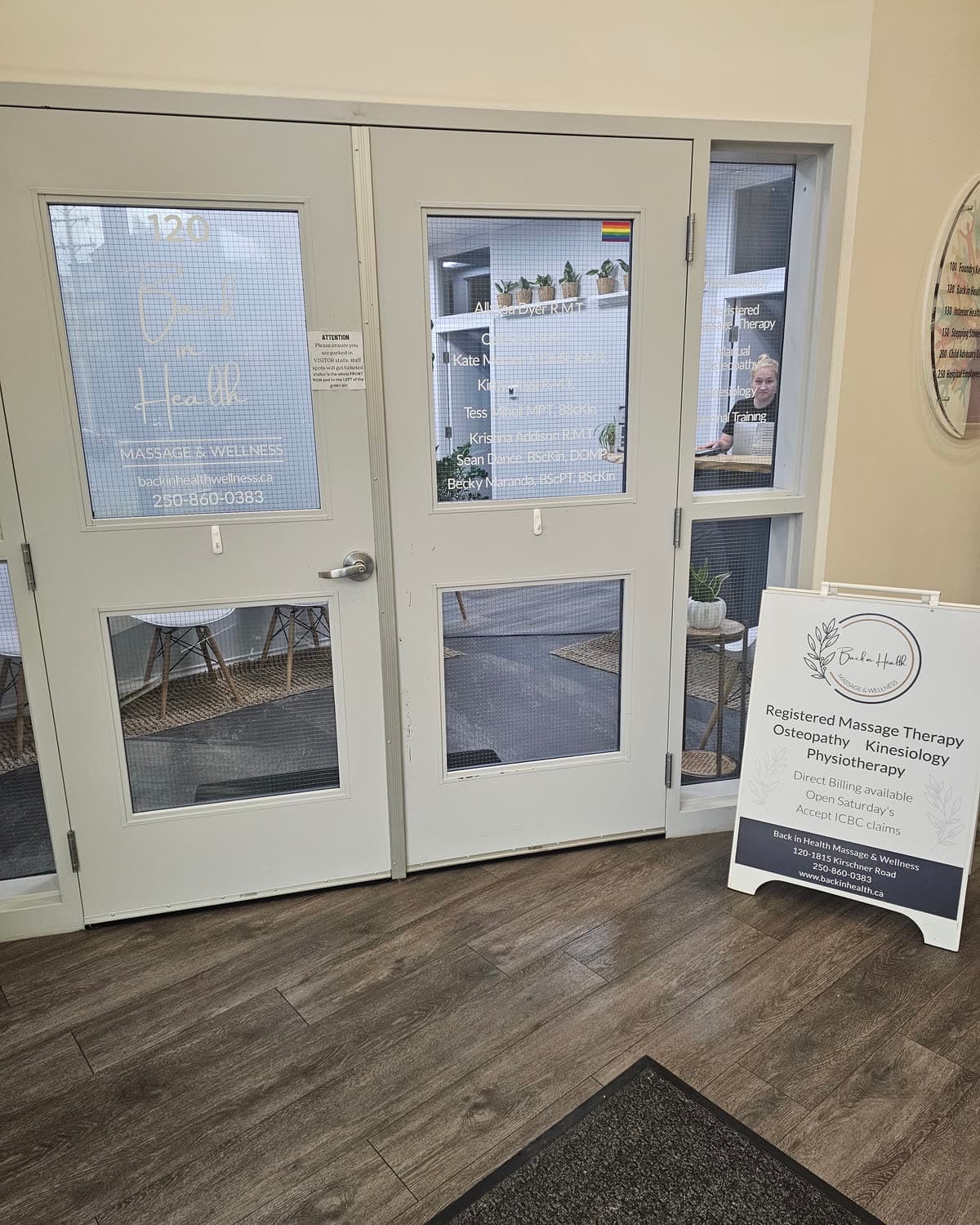 The glass entrance doors and welcome sign just inside Back in Health