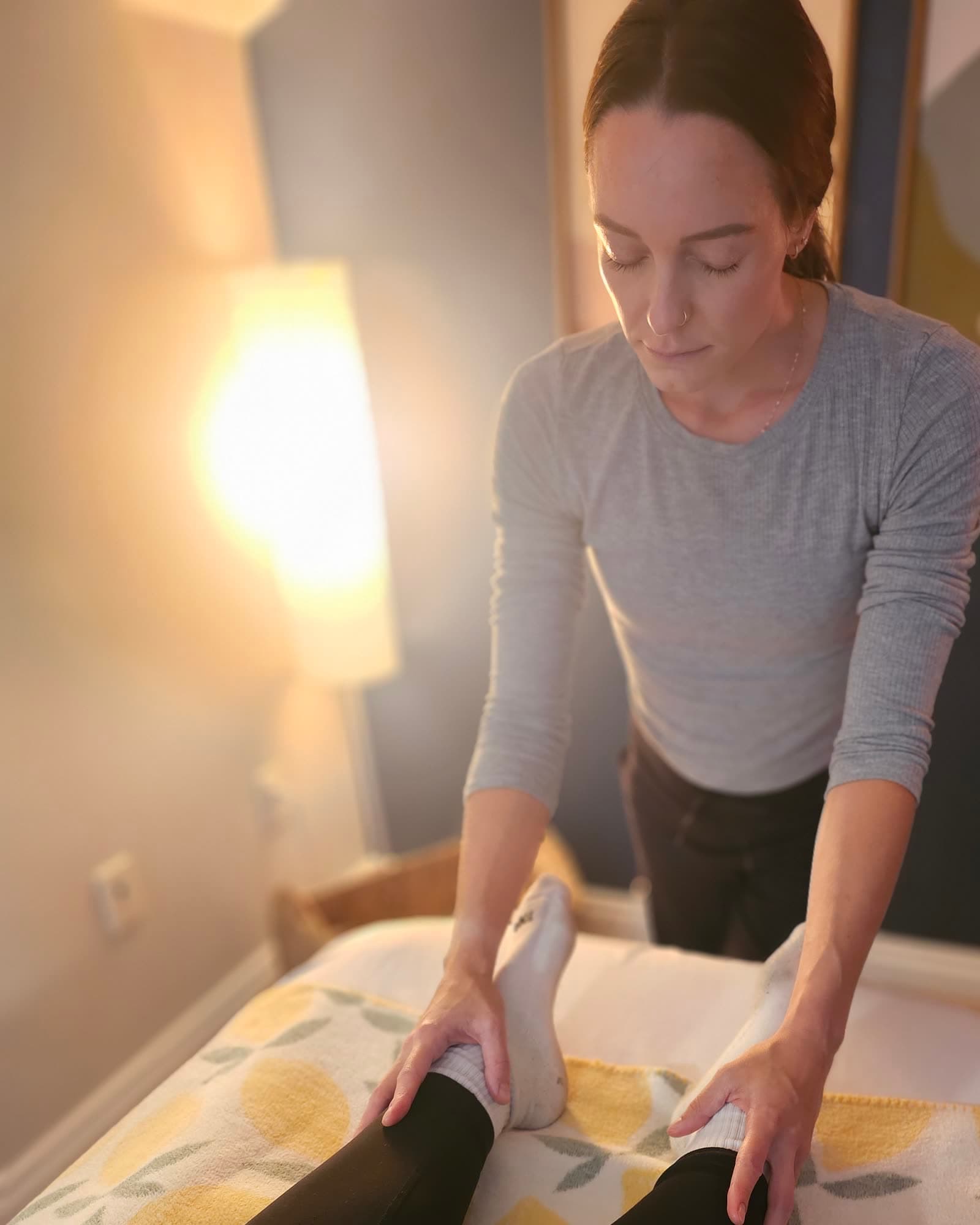 A practitioner guiding a client's leg through an assisted range-of-motion movement on the table