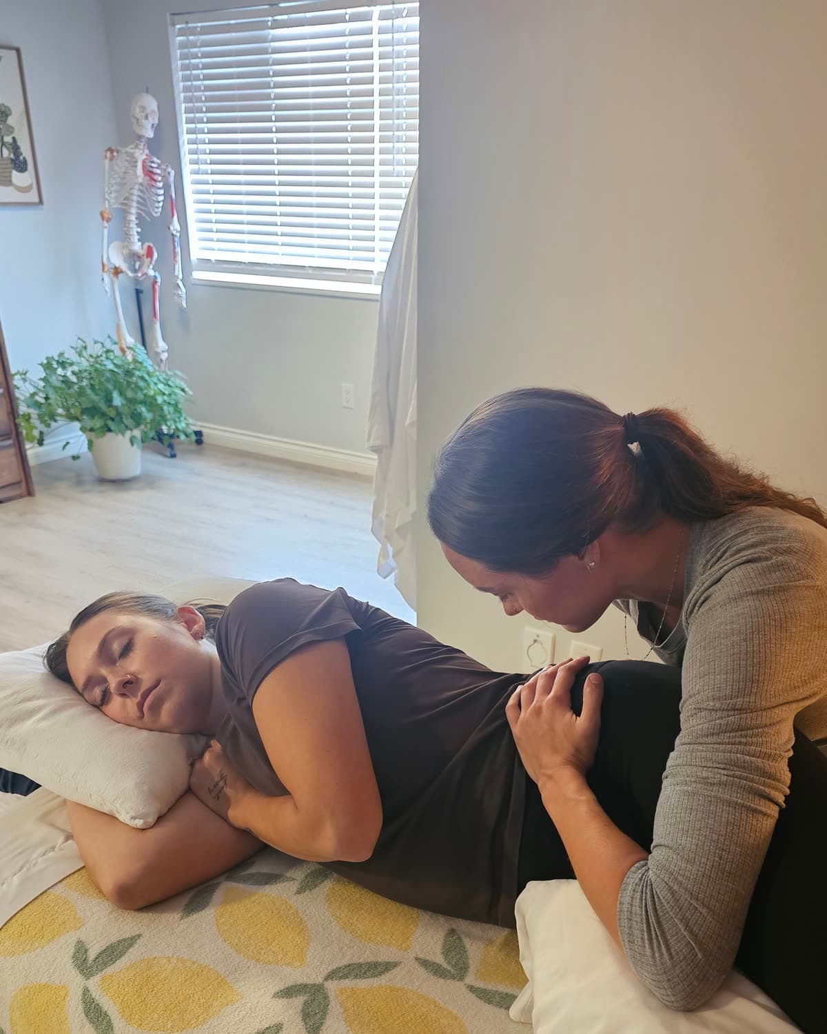A massage therapist treating a client lying on her side, supported by pillows, at Back in Health