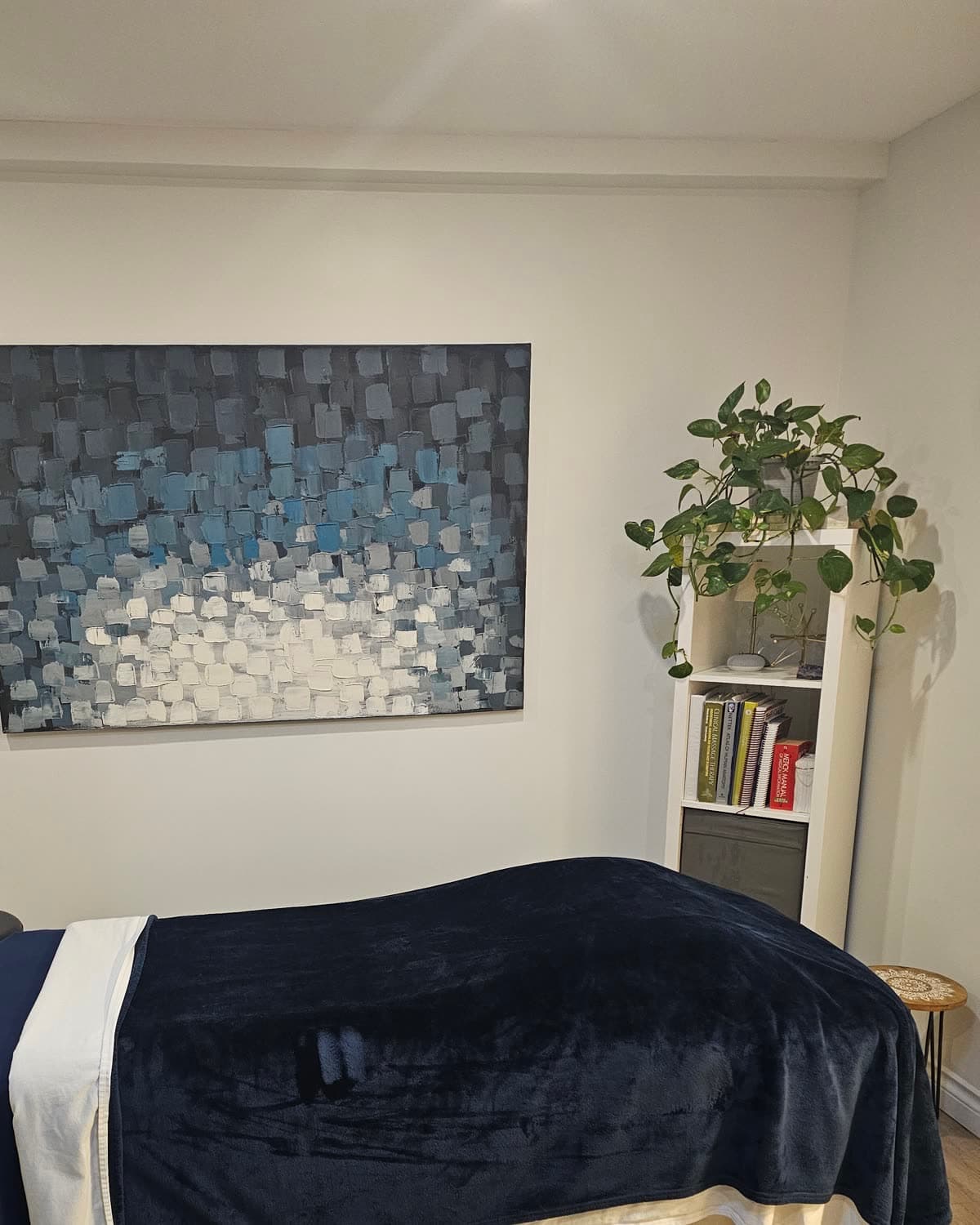 A treatment room at Back in Health with a navy-draped table and abstract blue artwork